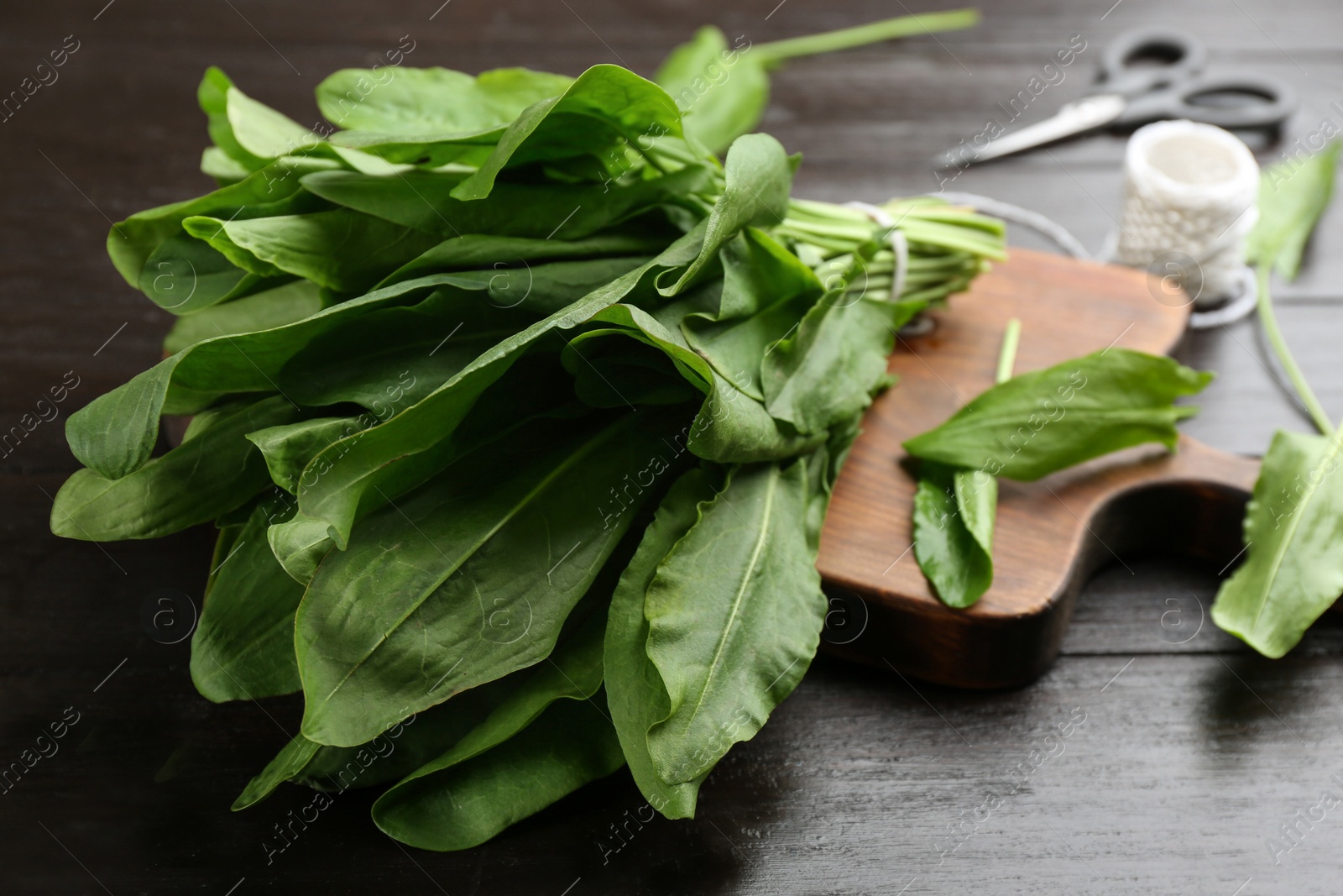 Photo of Fresh green sorrel leaves on black wooden table, closeup