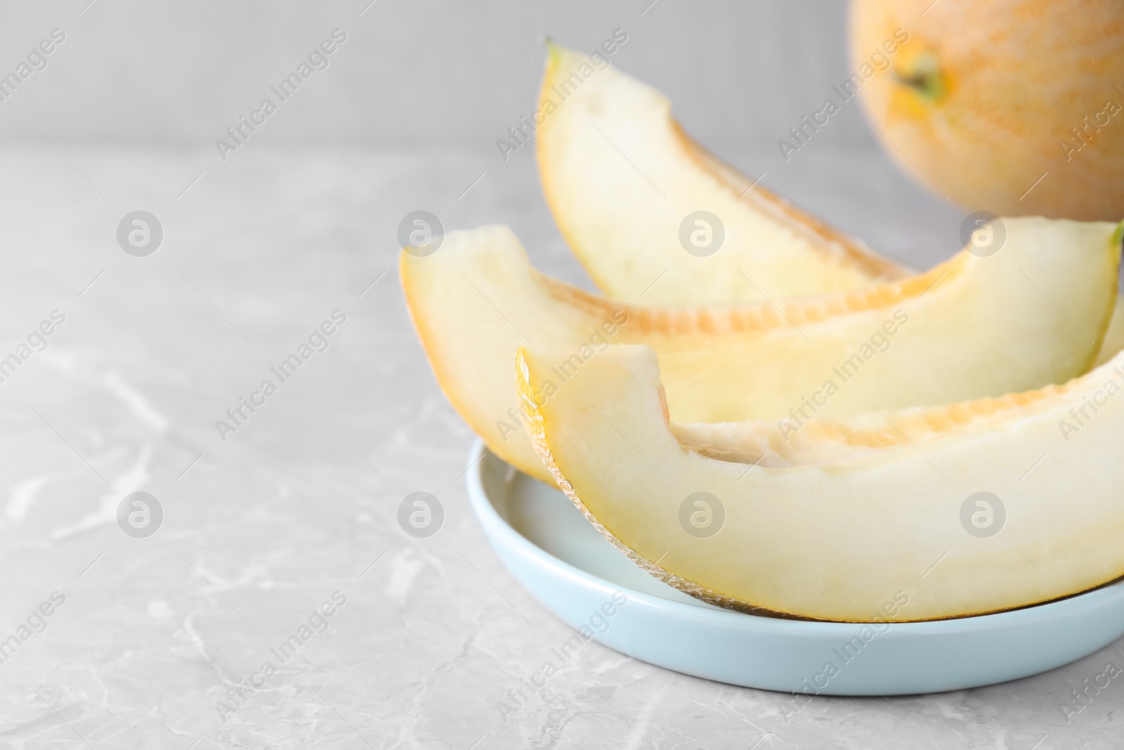 Photo of Pieces of delicious honeydew melon on light grey marble table