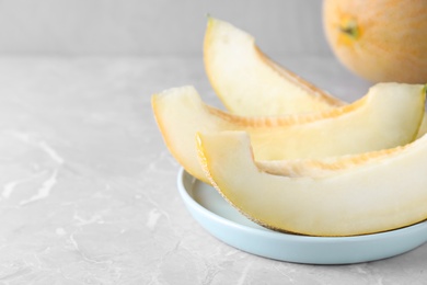 Pieces of delicious honeydew melon on light grey marble table