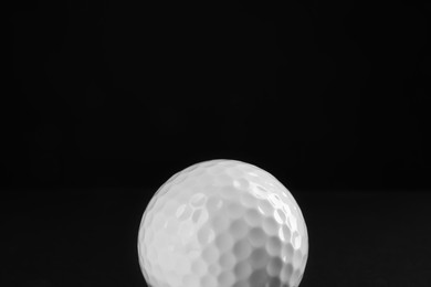 Photo of Golf ball on black background, closeup. Space for text