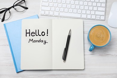 Message Hello Monday written in notebook, computer keyboard and cup of coffee on white wooden desk, flat lay