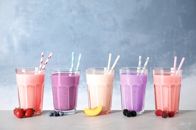 Tasty milk shakes and ingredients on table against blue background