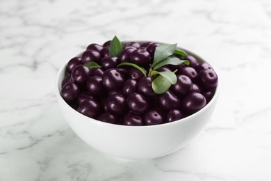 Fresh acai berries in bowl on white marble table, closeup