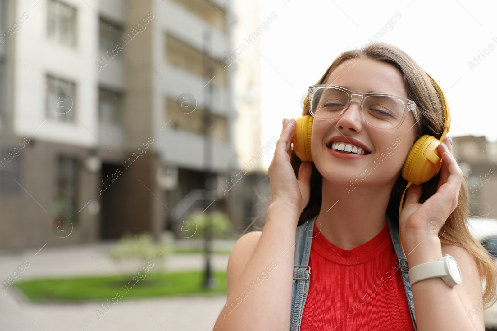 Photo of Beautiful young woman listening to music with headphones on sunny day outdoors, space for text