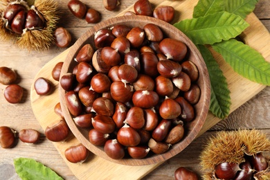 Fresh sweet edible chestnuts on wooden table, flat lay