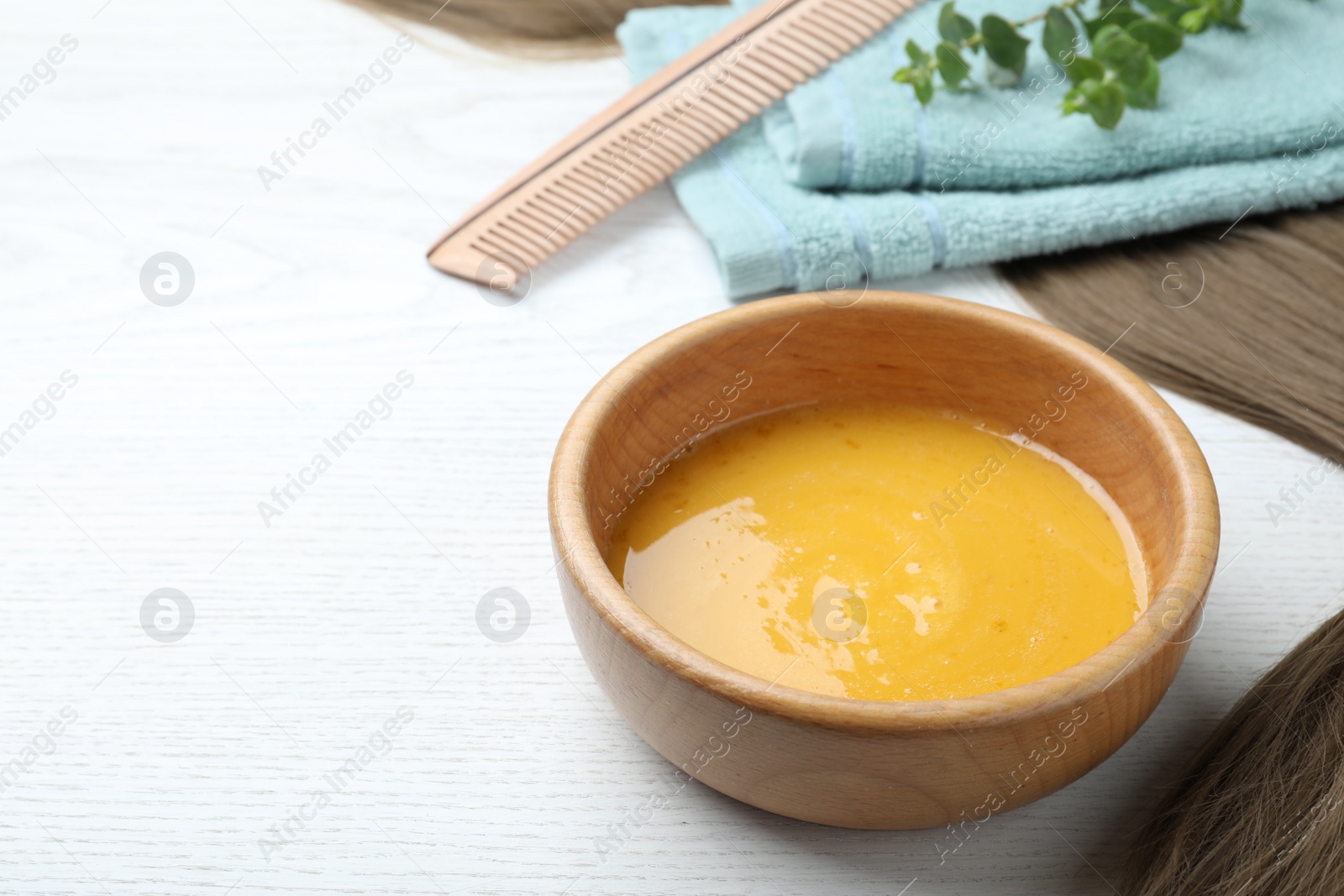 Photo of Homemade hair mask in bowl on white wooden table. Space for text