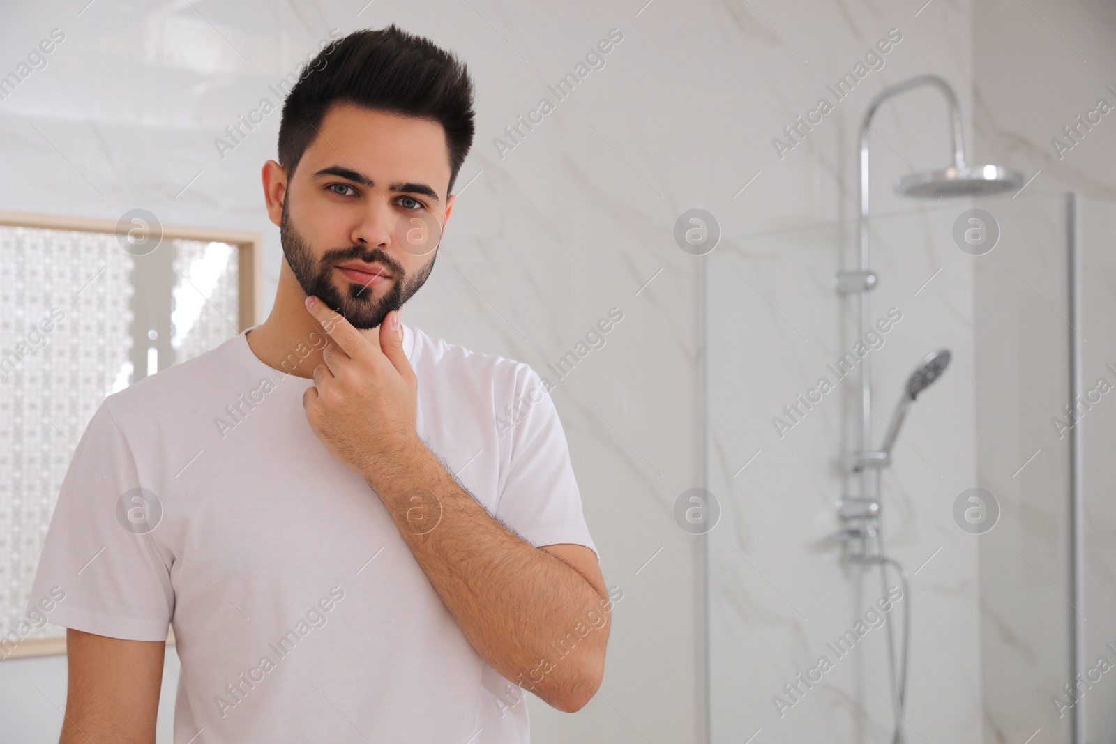 Photo of Handsome young man after shaving in bathroom, space for text