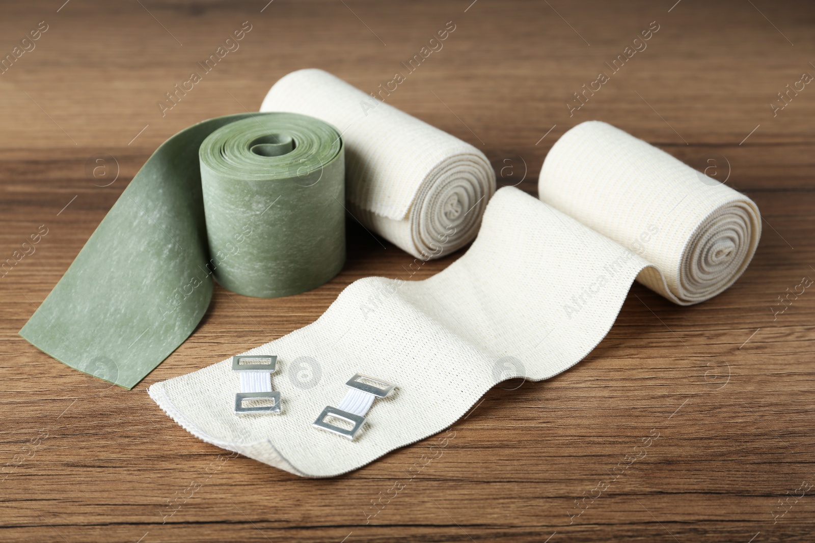 Photo of Different medical bandage rolls on wooden background