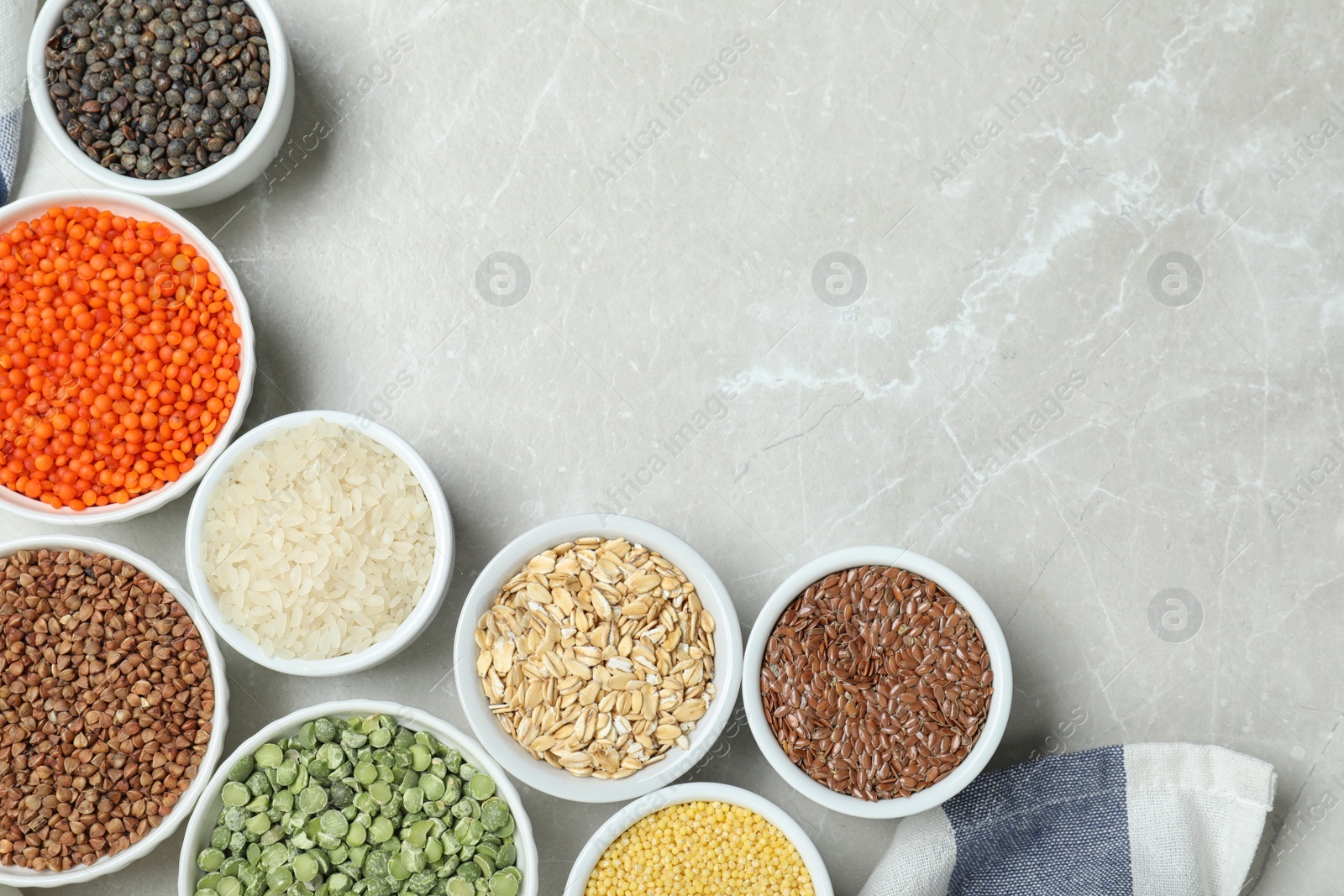 Photo of Flat lay composition with different types of legumes and cereals on grey marble table, space for text. Organic grains