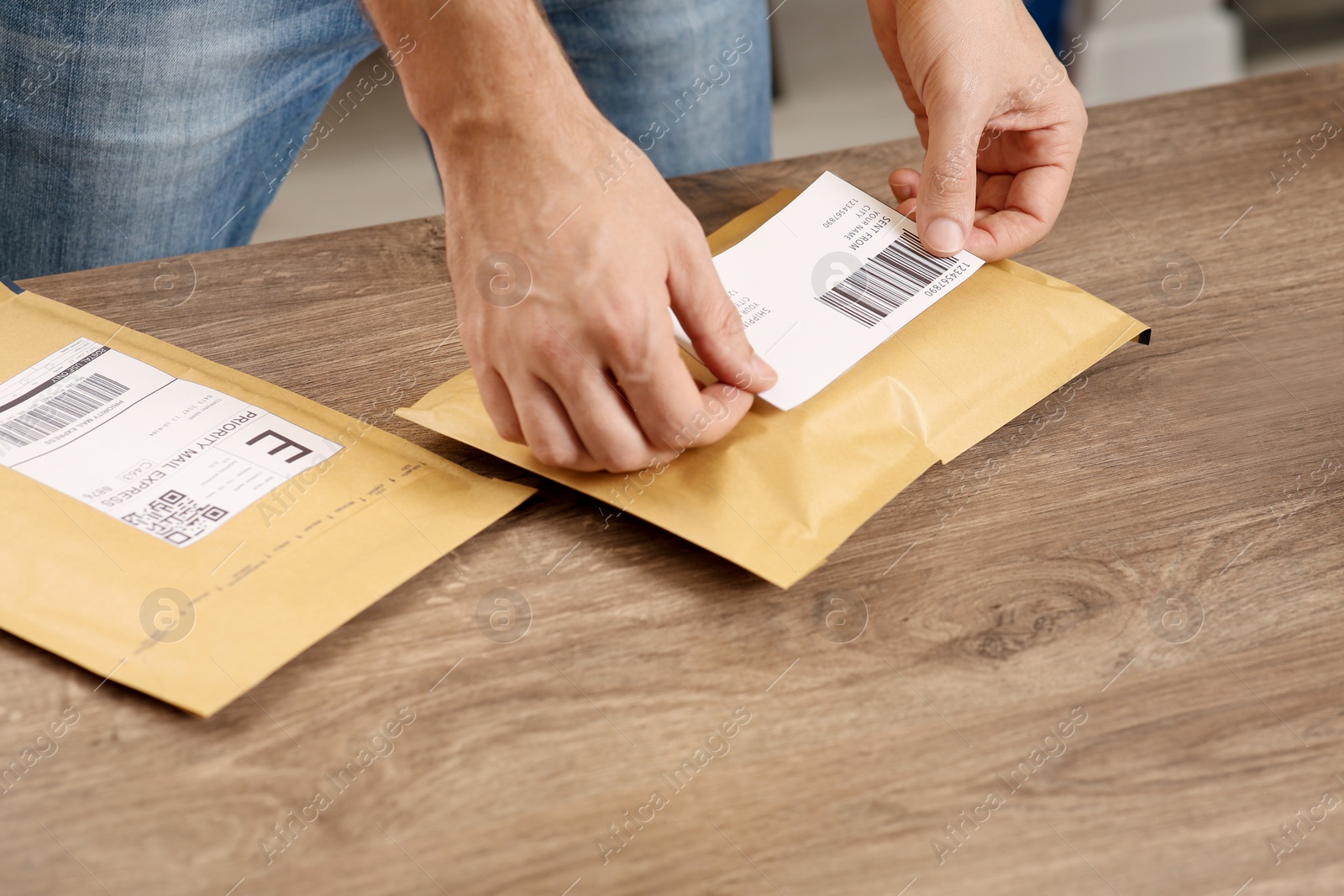 Photo of Post office worker sticking barcode on parcel at counter indoors, closeup