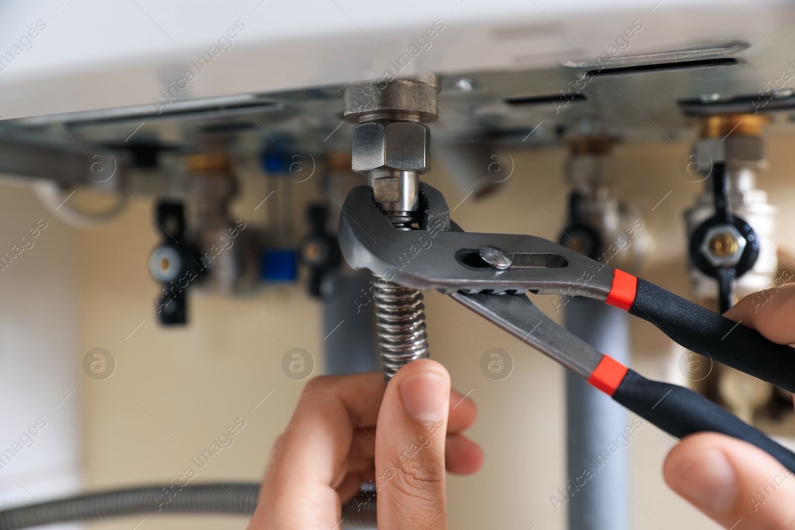 Photo of Man repairing gas boiler with waterpump plier, closeup