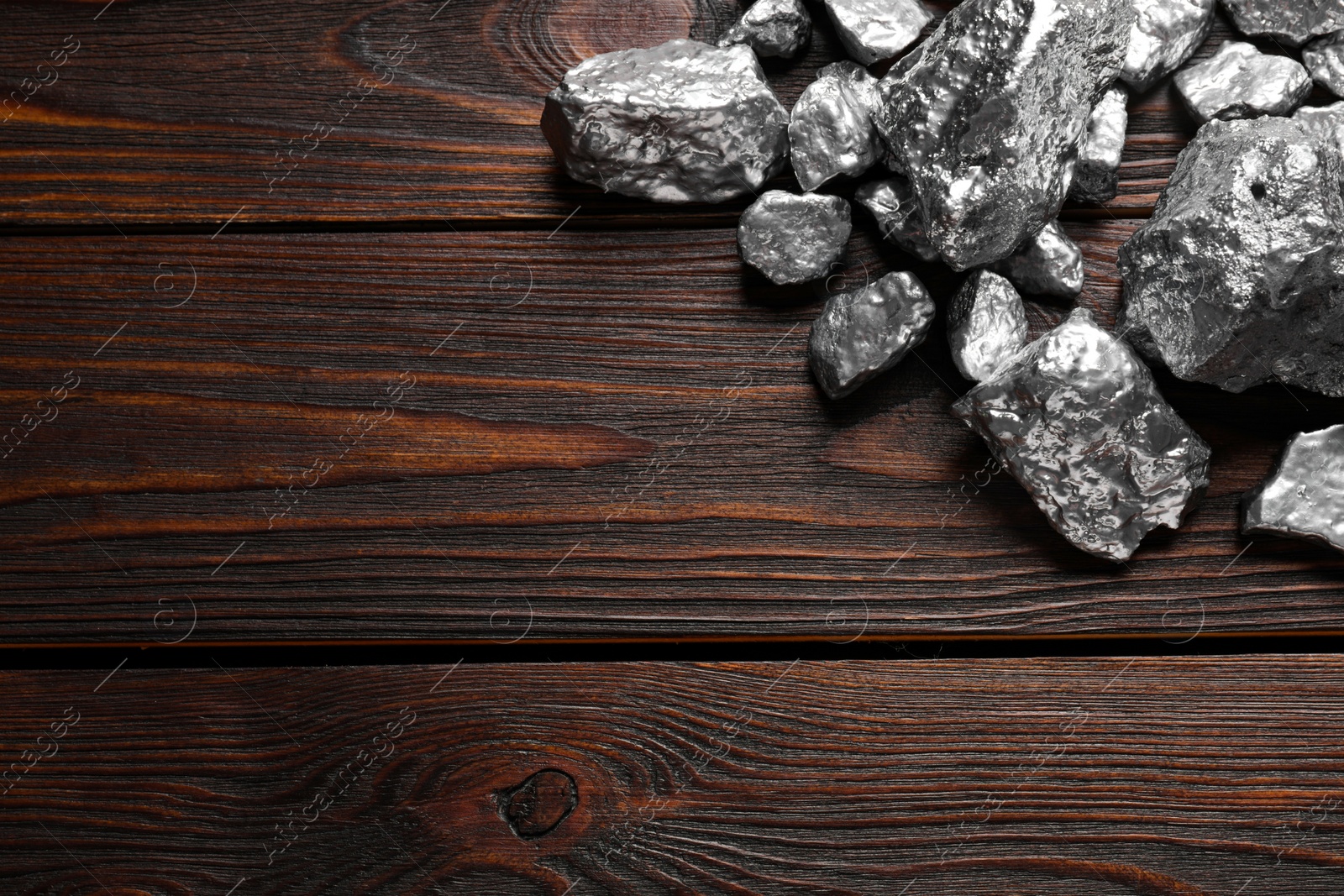 Photo of Pile of silver nuggets on wooden table, flat lay. Space for text