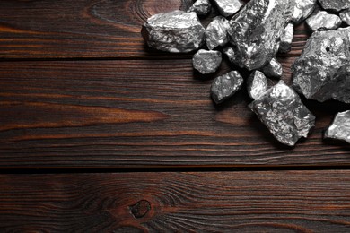 Photo of Pile of silver nuggets on wooden table, flat lay. Space for text