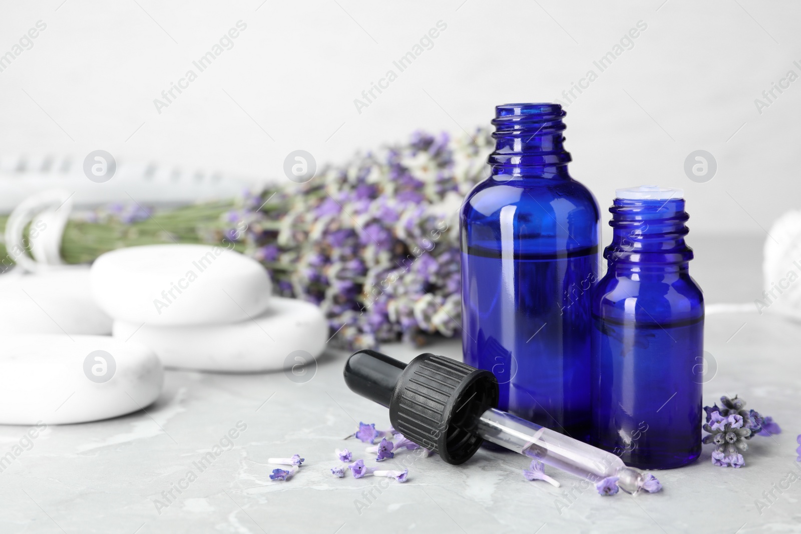 Photo of Bottles with natural lavender essential oil on table, space for text