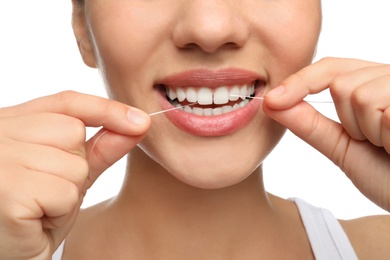 Young woman flossing her teeth on white background, closeup. Cosmetic dentistry