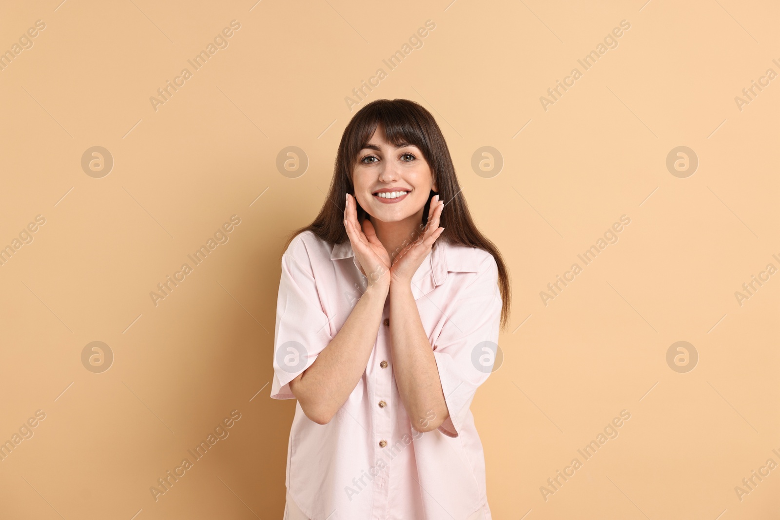 Photo of Happy woman wearing pyjama on beige background