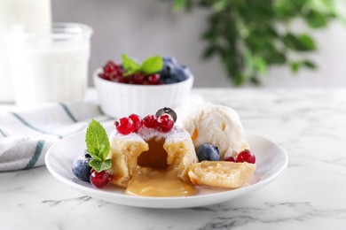 Photo of Tasty vanilla fondant with white chocolate, berries and ice cream on white marble table
