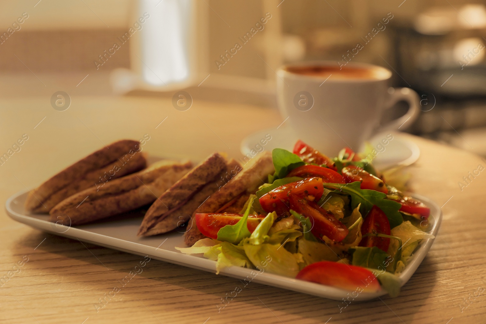 Photo of Plate of delicious toasts with salad and coffee cup on wooden table in cafe, closeup