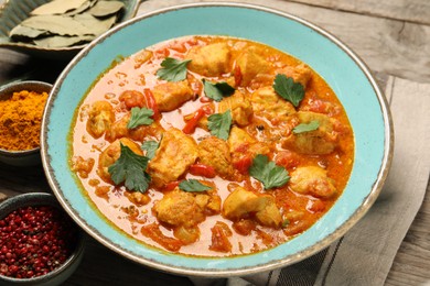 Delicious chicken curry and ingredients on wooden table