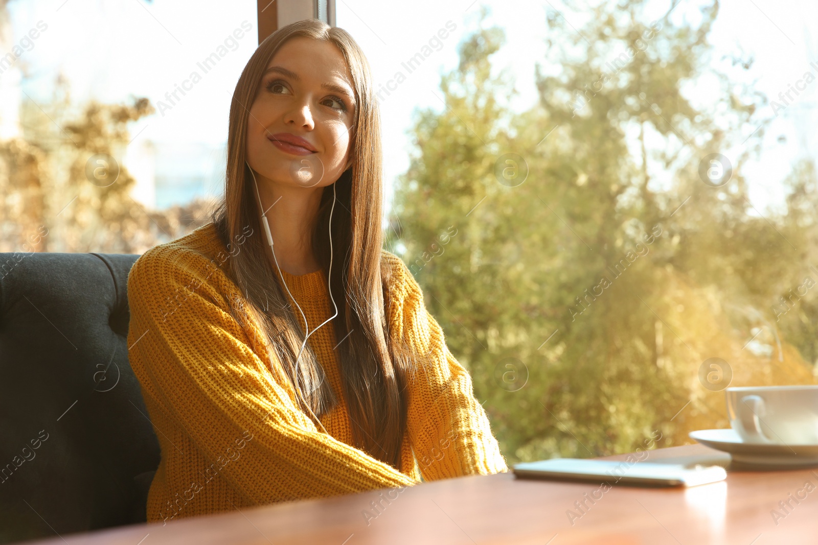 Photo of Woman listening to audiobook at table in cafe