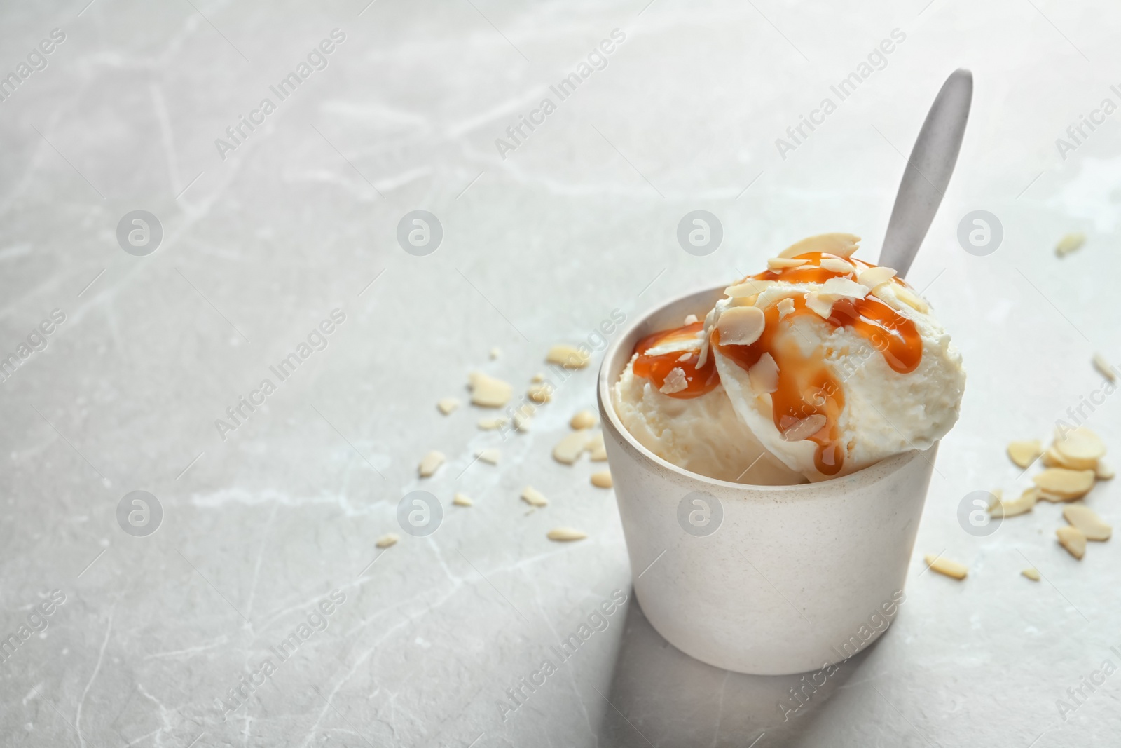 Photo of Bowl with caramel ice cream on light background