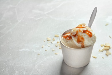 Bowl with caramel ice cream on light background