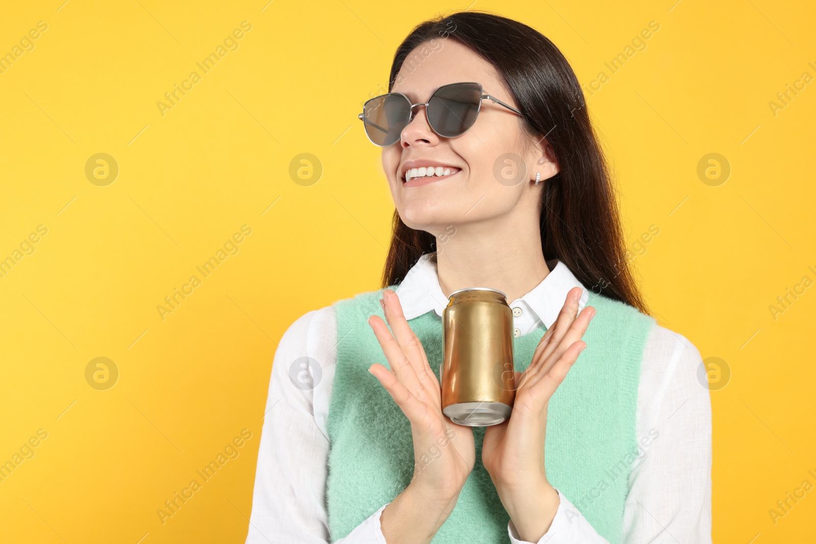 Photo of Beautiful happy woman holding beverage can on yellow background. Space for text