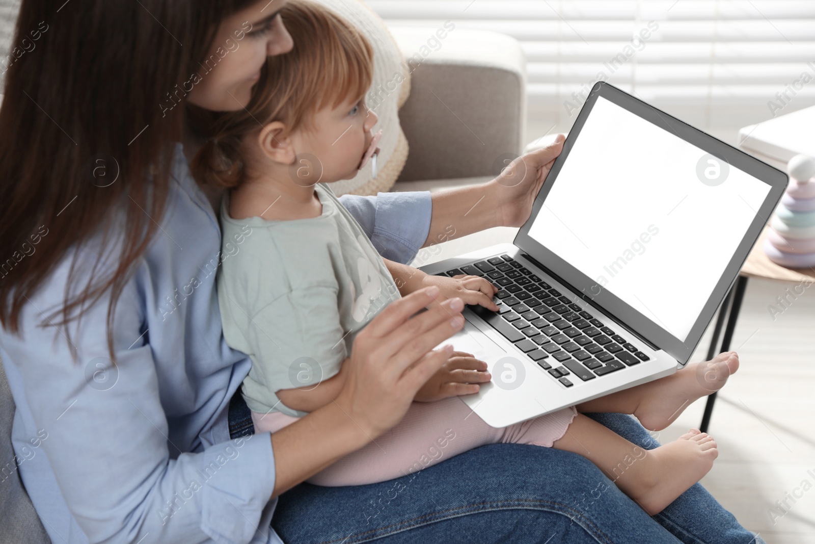 Photo of Mother and daughter sitting with laptop on sofa at home. Pediatrician online consultation