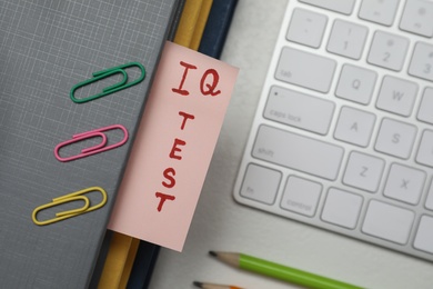 Photo of Paper with words IQ Test in notebook, keyboard and fasteners on office table, flat lay