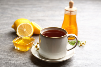 Photo of Tea with honey and lemon on grey table