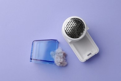 Photo of Fabric shaver with fuzz on lilac background, flat lay