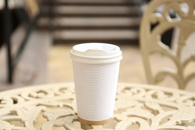 Photo of Paper cup of coffee on table outdoors, closeup. Takeaway drink