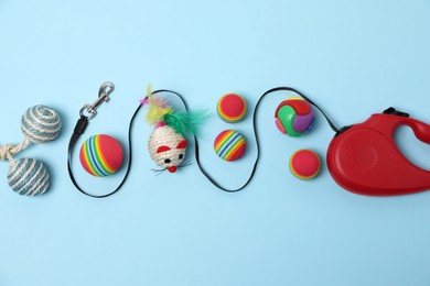 Flat lay composition with red pet retractable leash and toys on light blue background