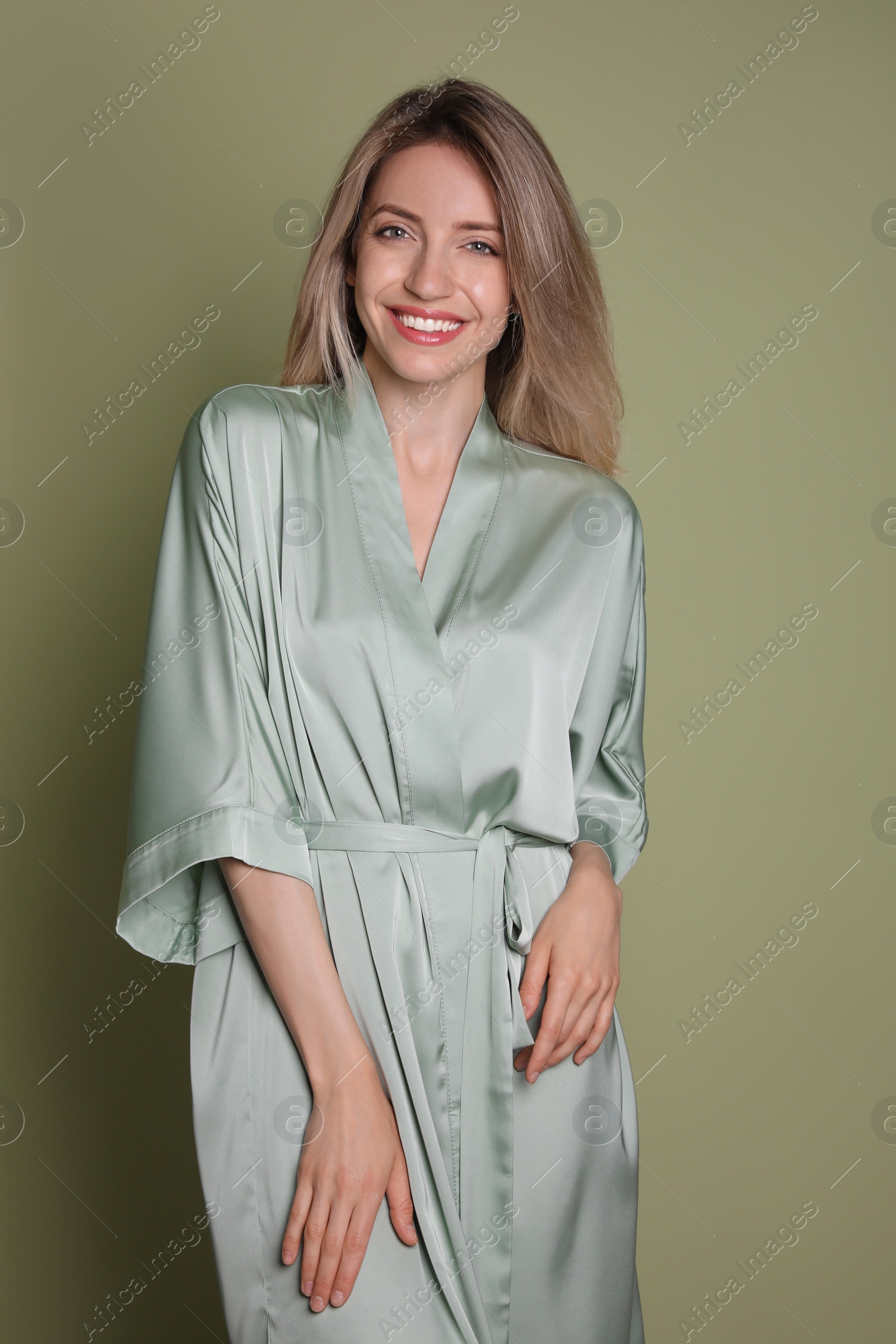 Photo of Pretty young woman in beautiful light green silk robe on olive background