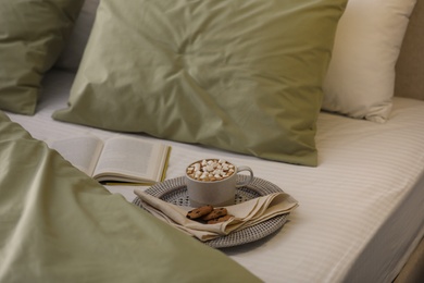 Photo of Cup of drink, cookies and book on bed with new pistachio linens