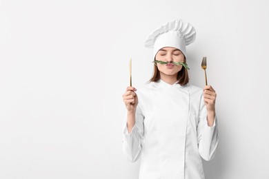 Photo of Professional chef with rosemary and cutlery having fun on light background. Space for text