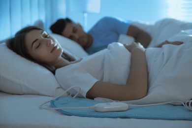 Photo of Couple sleeping on electric heating pad in bed at night
