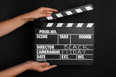 Photo of Woman with clapperboard against dark background, closeup. Black Friday concept