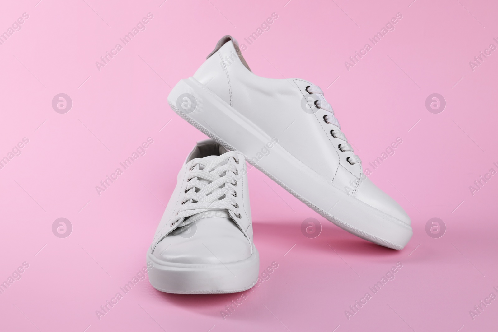 Photo of Pair of stylish white sneakers on pink background