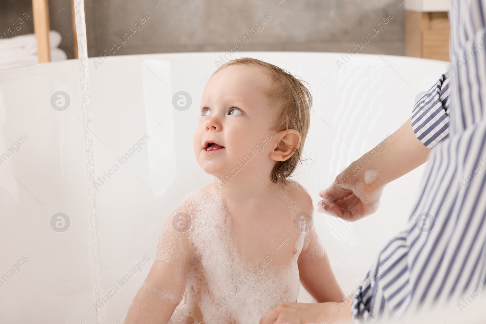 Photo of Mother washing her little baby in tub at home, closeup