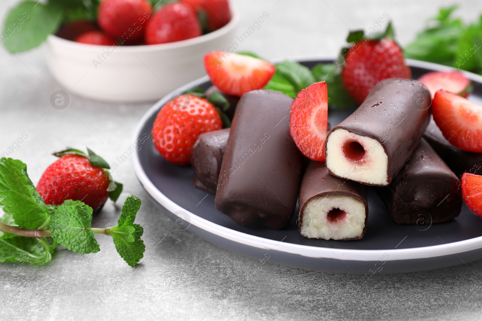 Photo of Delicious glazed curd snacks with fresh strawberries and mint on light grey table, closeup