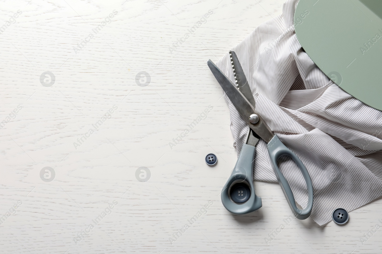 Photo of Scissors, buttons and fabric on light background, top view. Tailoring equipment