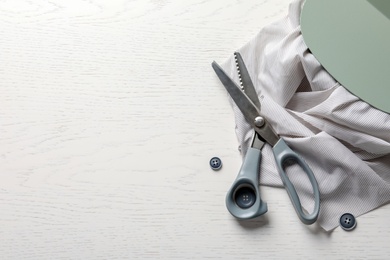 Scissors, buttons and fabric on light background, top view. Tailoring equipment