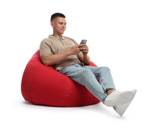 Handsome man with smartphone on red bean bag chair against white background