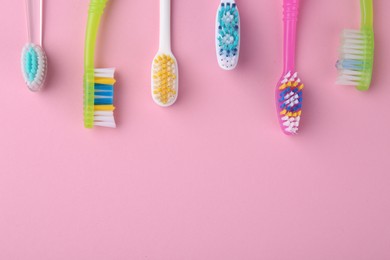 Photo of Many different toothbrushes on pink background, flat lay. Space for text