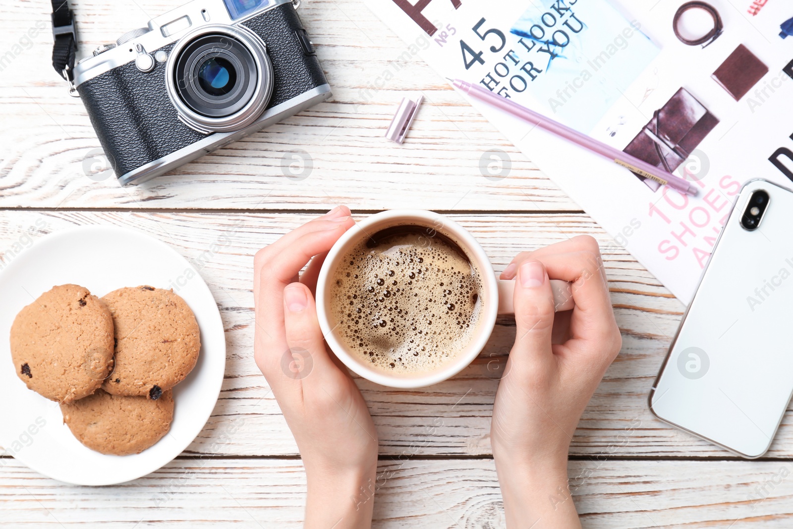 Photo of Young woman with cup of delicious hot coffee at table, top view