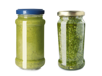 Delicious pesto sauce in glass jars on white background