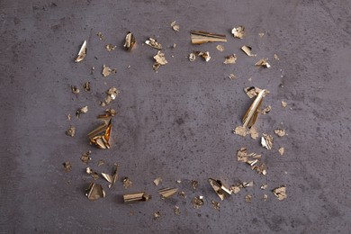 Photo of Frame of edible gold leaf on grey textured table, flat lay. Space for text