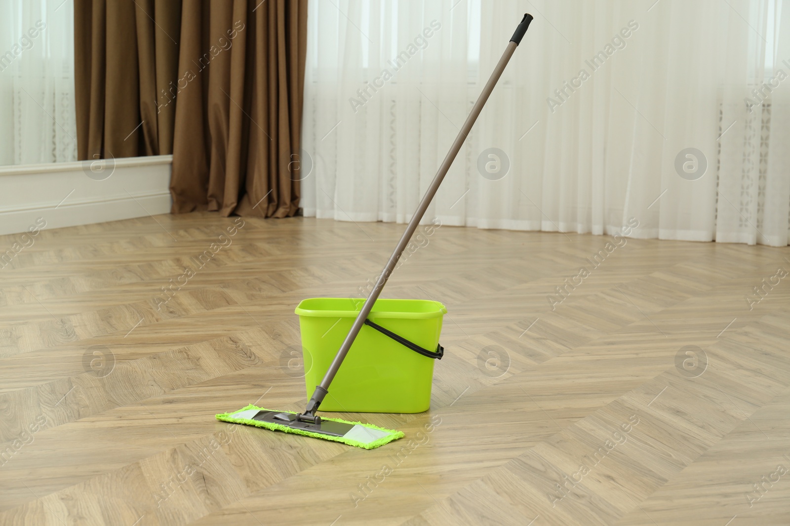 Photo of Bucket and mop on floor at home. Cleaning equipment