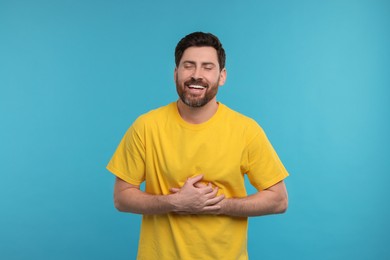 Handsome man laughing on light blue background